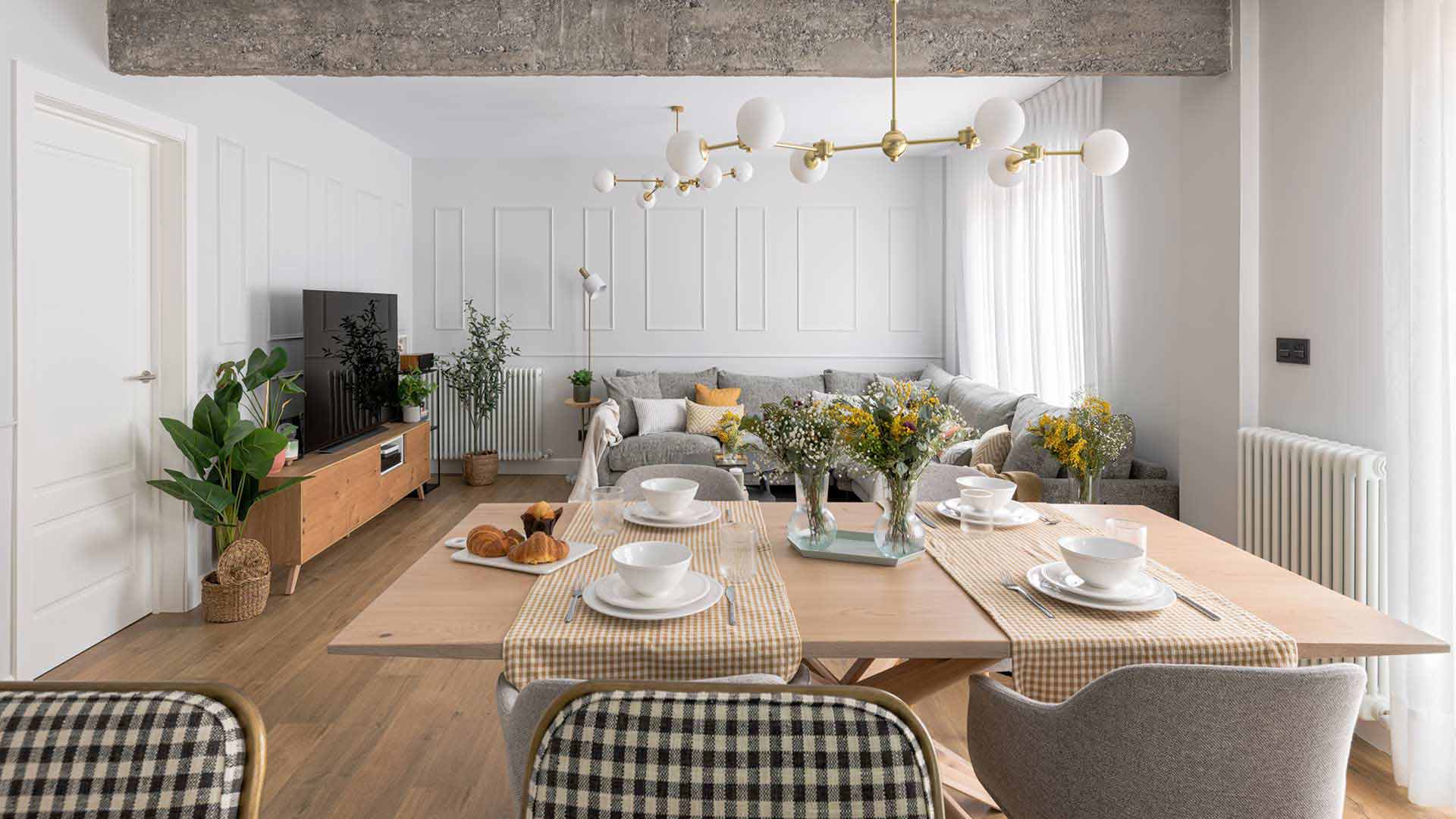 Salón comedor de diseño moderno con viga de hormigón visto y sofá esquinero gris. Foto Manu Luque